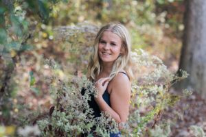 Outdoor portrait amid flowering branches and greenery in natural lighting.
