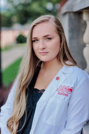 Portrait senior shot of a nursing student wearing a white medical coat with university logo at JSU.
