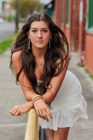 An artistic portrait against brick wall featuring a white dress and flowing hair.