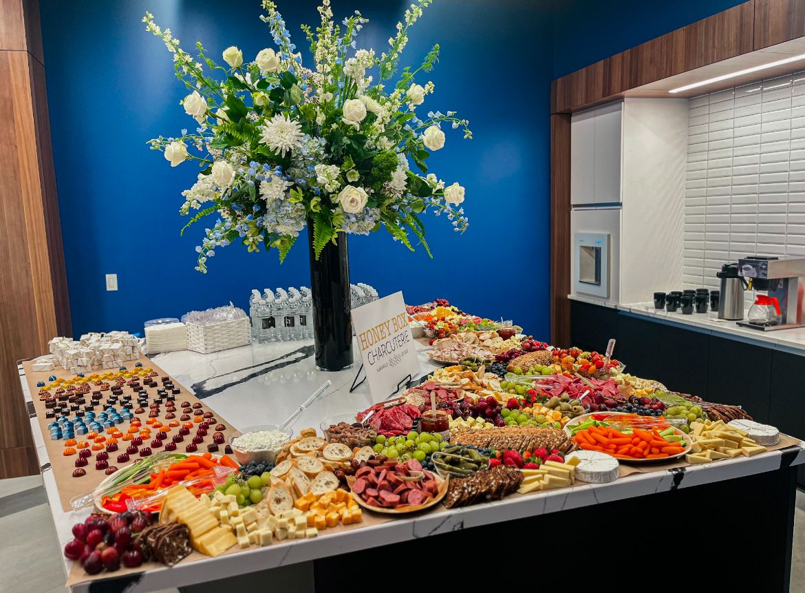 Elegant charcuterie display with colorful fruits, meats, and cheeses arranged on dark wooden tables.