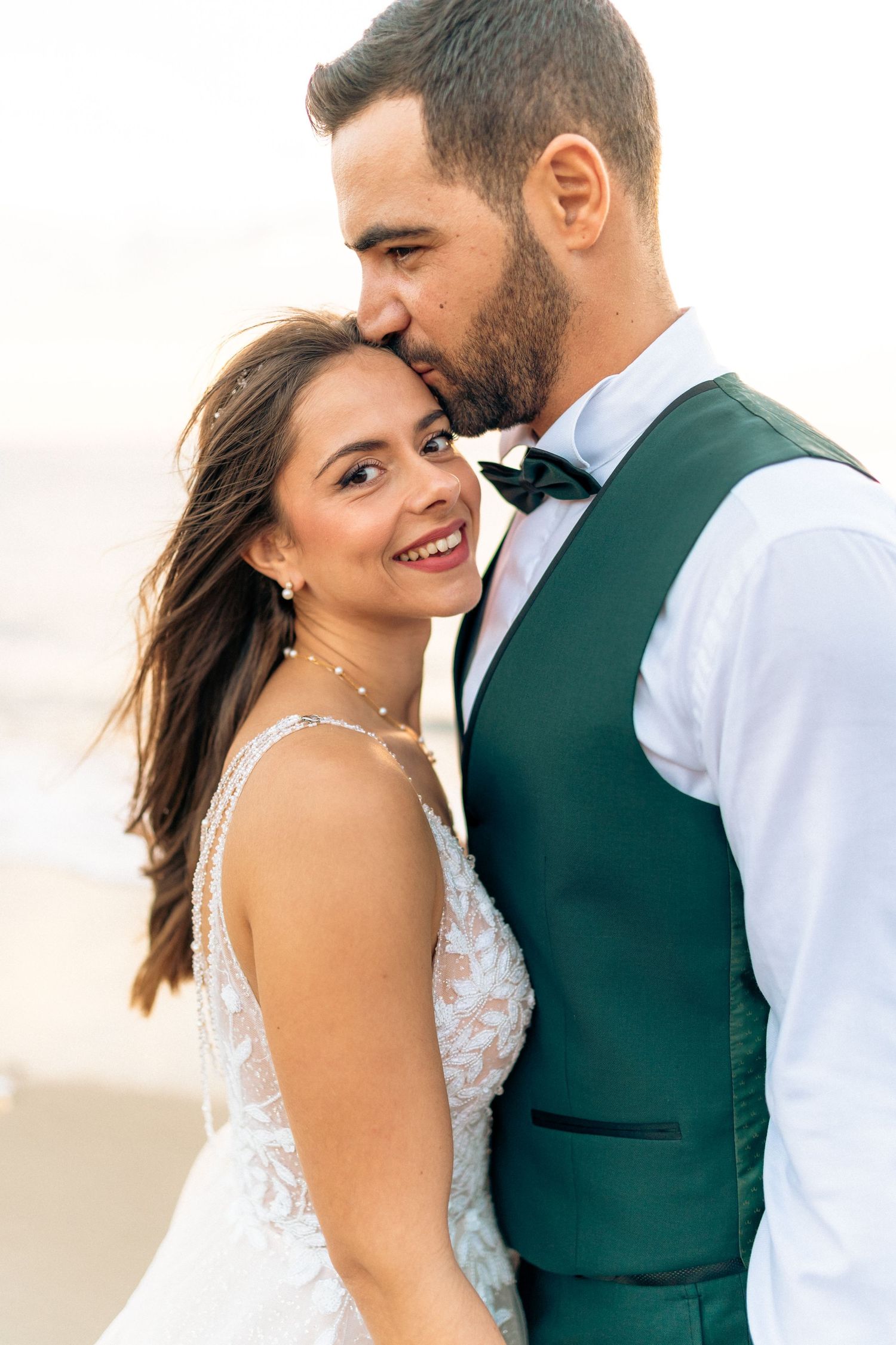 Intimate wedding portrait of a couple in formal attire by the sea.