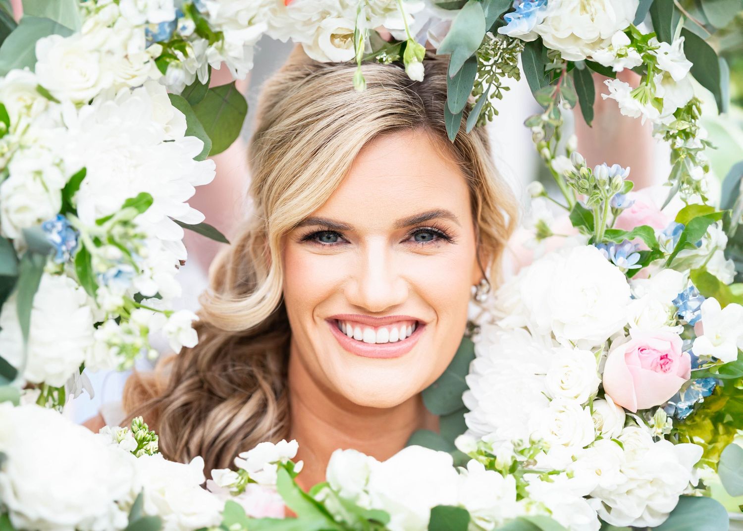 Close up portrait framed by white and pink flowers and greenery.