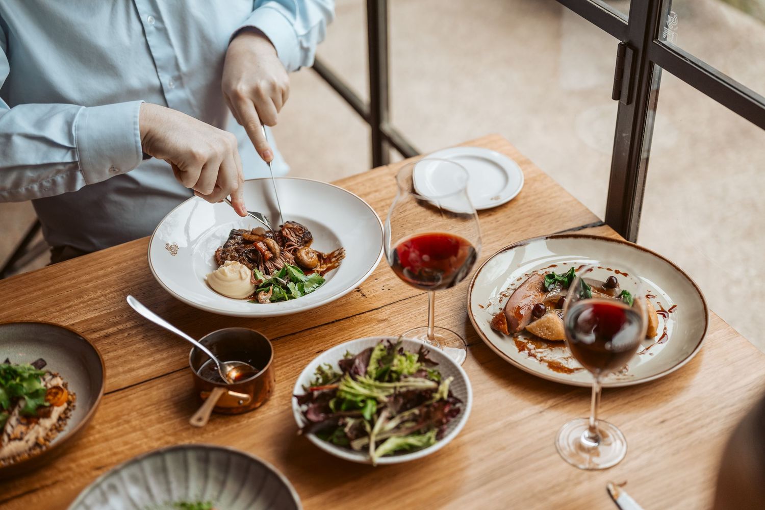 Fine dining experience with multiple courses and wine glasses on wooden table