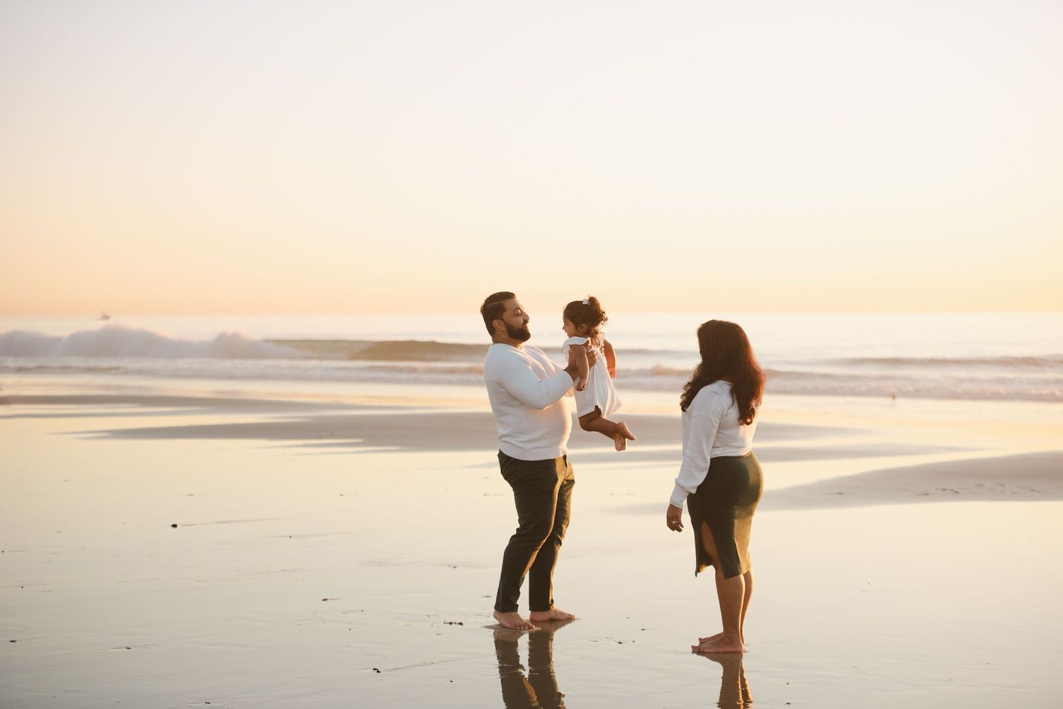 Family of three playing together during a beautiful picturesque sunset in Southern California.