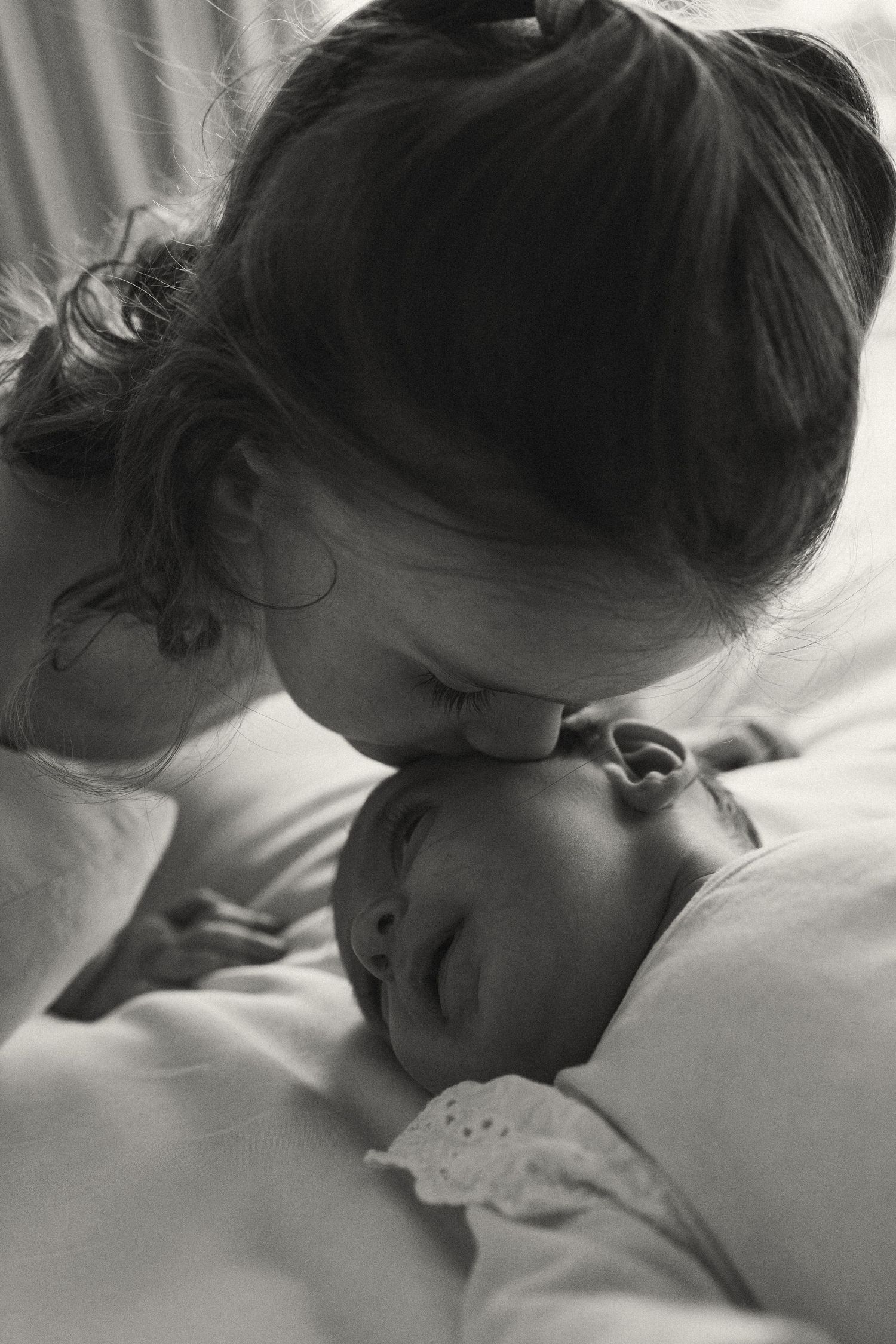 Intimate black and white photo of tender moment between parent and child in bed.