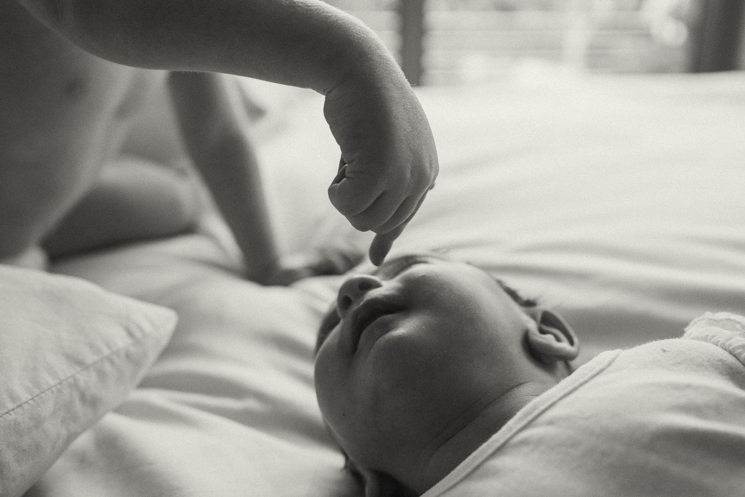 Close-up detail of hands against white bedding.