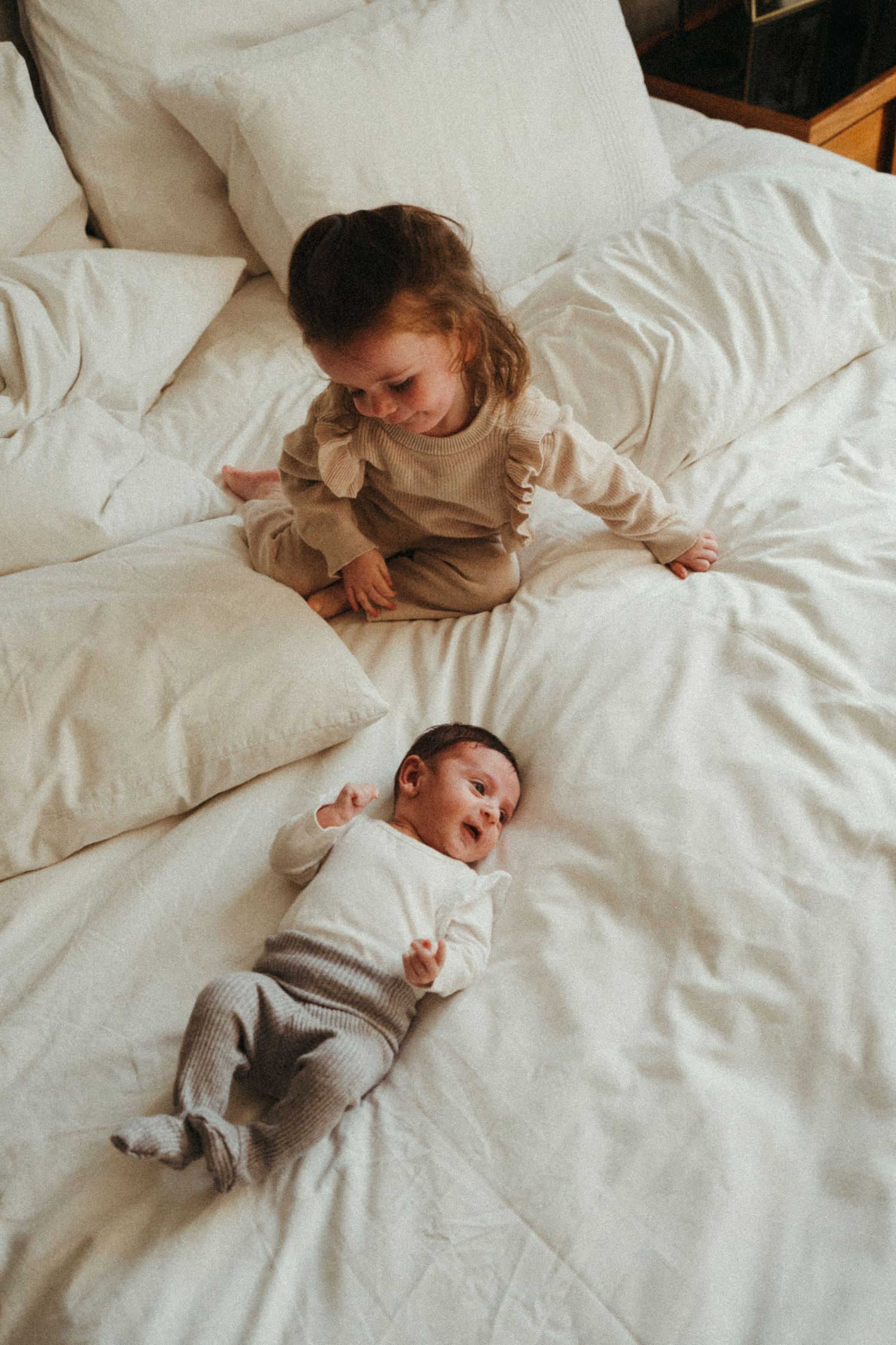Two children sharing a peaceful moment together on white bedding.