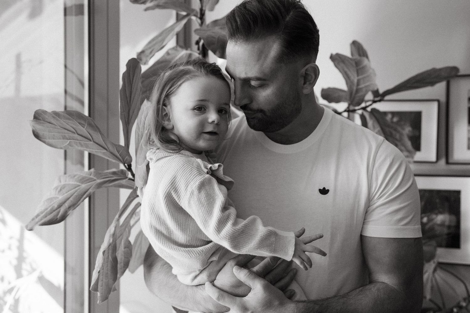 Black and white portrait showing intimate family bonding against a light background.