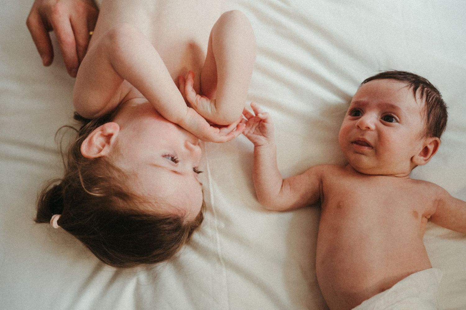 Gentle candid moments captured on white bedding in natural light.