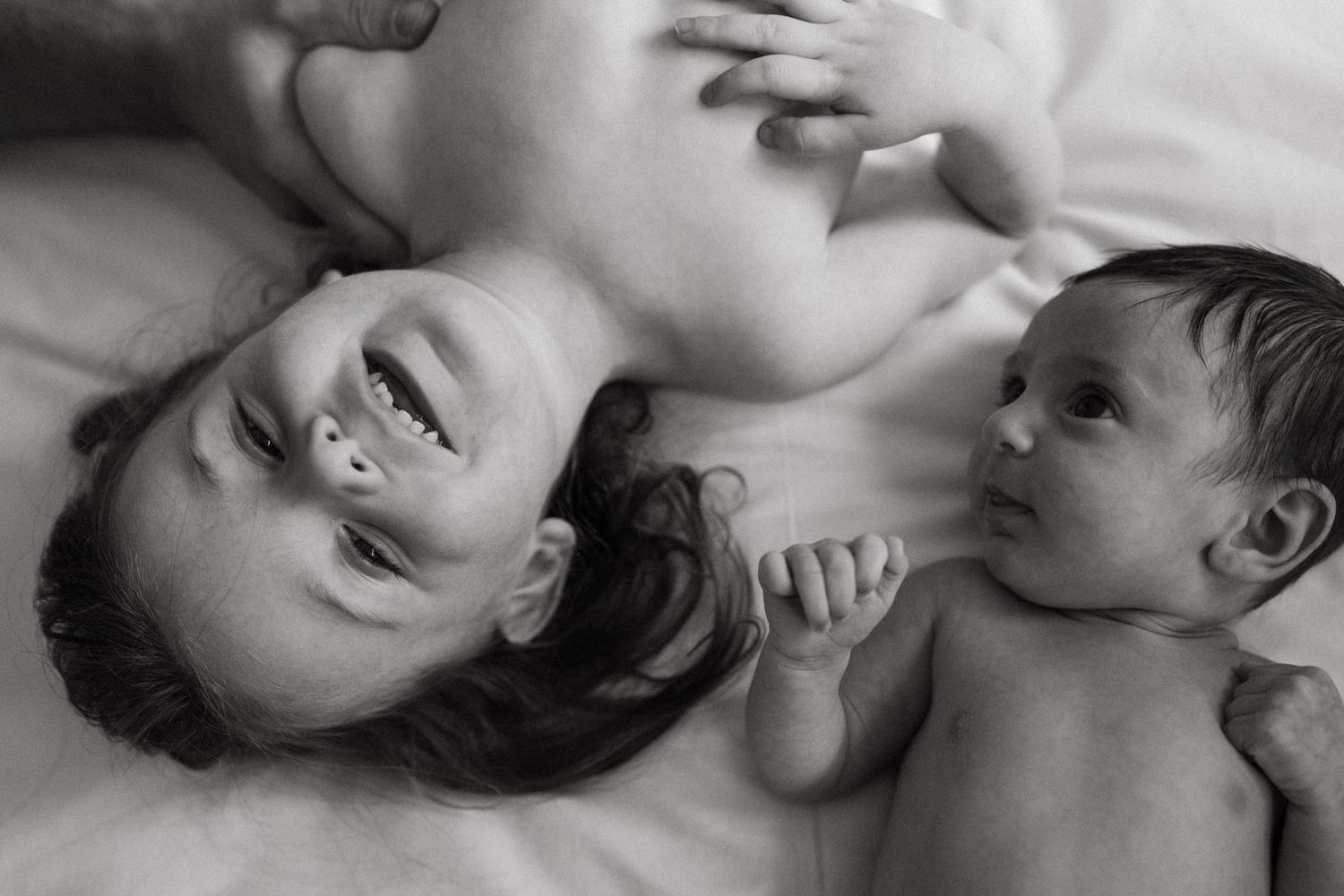 Intimate black and white close-up portraits on light colored bedding.