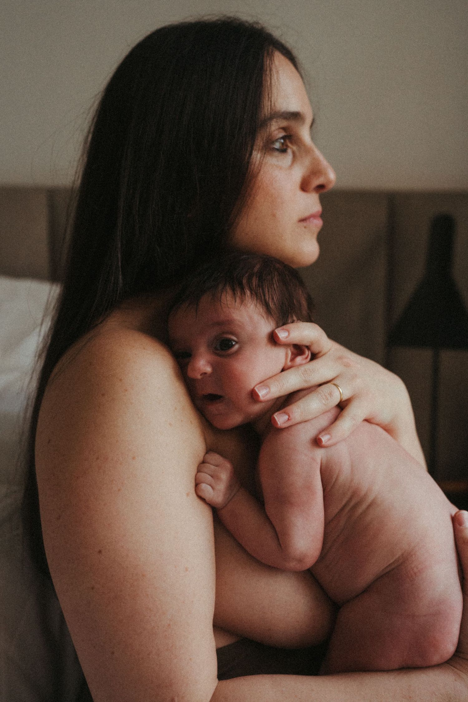 Side profile portrait capturing gentle moment between parent and newborn baby.