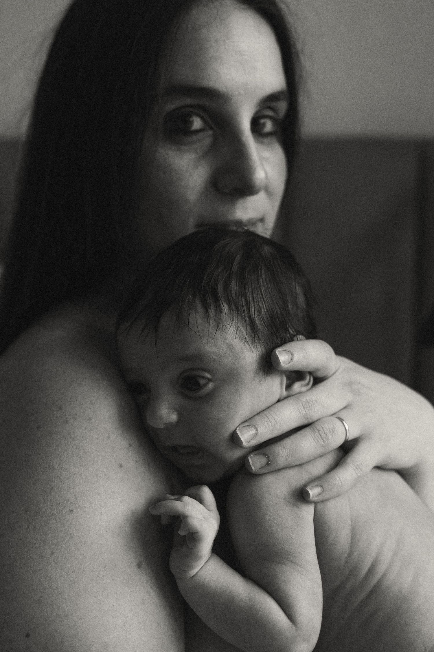 Dramatic black and white photograph showing protective embrace of parent and infant.