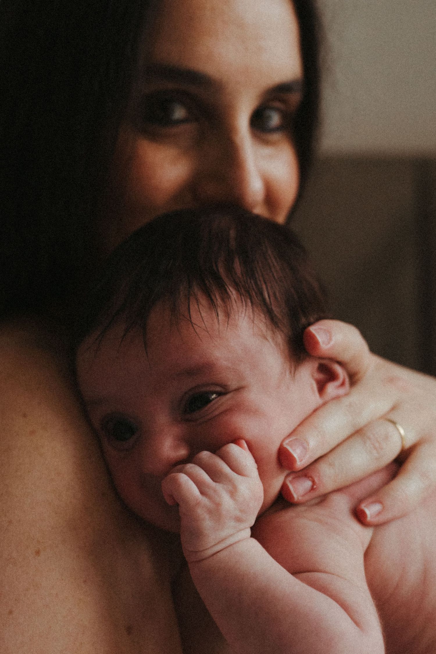 Intimate portrait showing parent cradling infant with gentle hands.