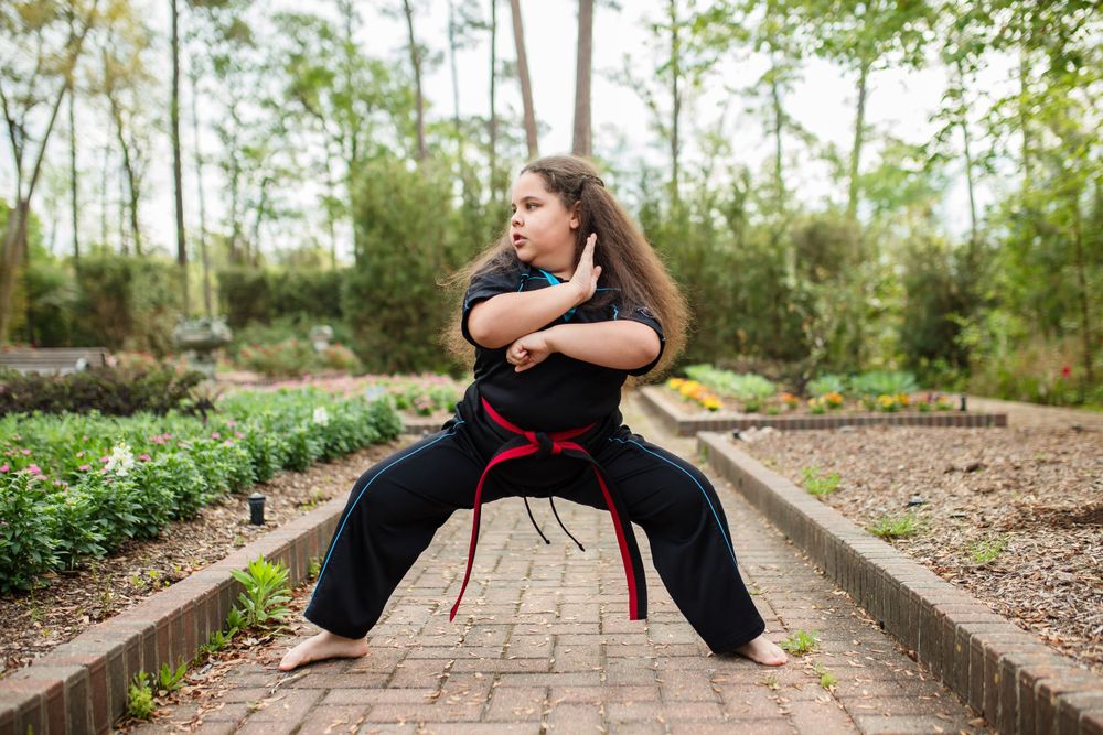 A girl with a black belt does karate at Mercer Botanical Gardens.