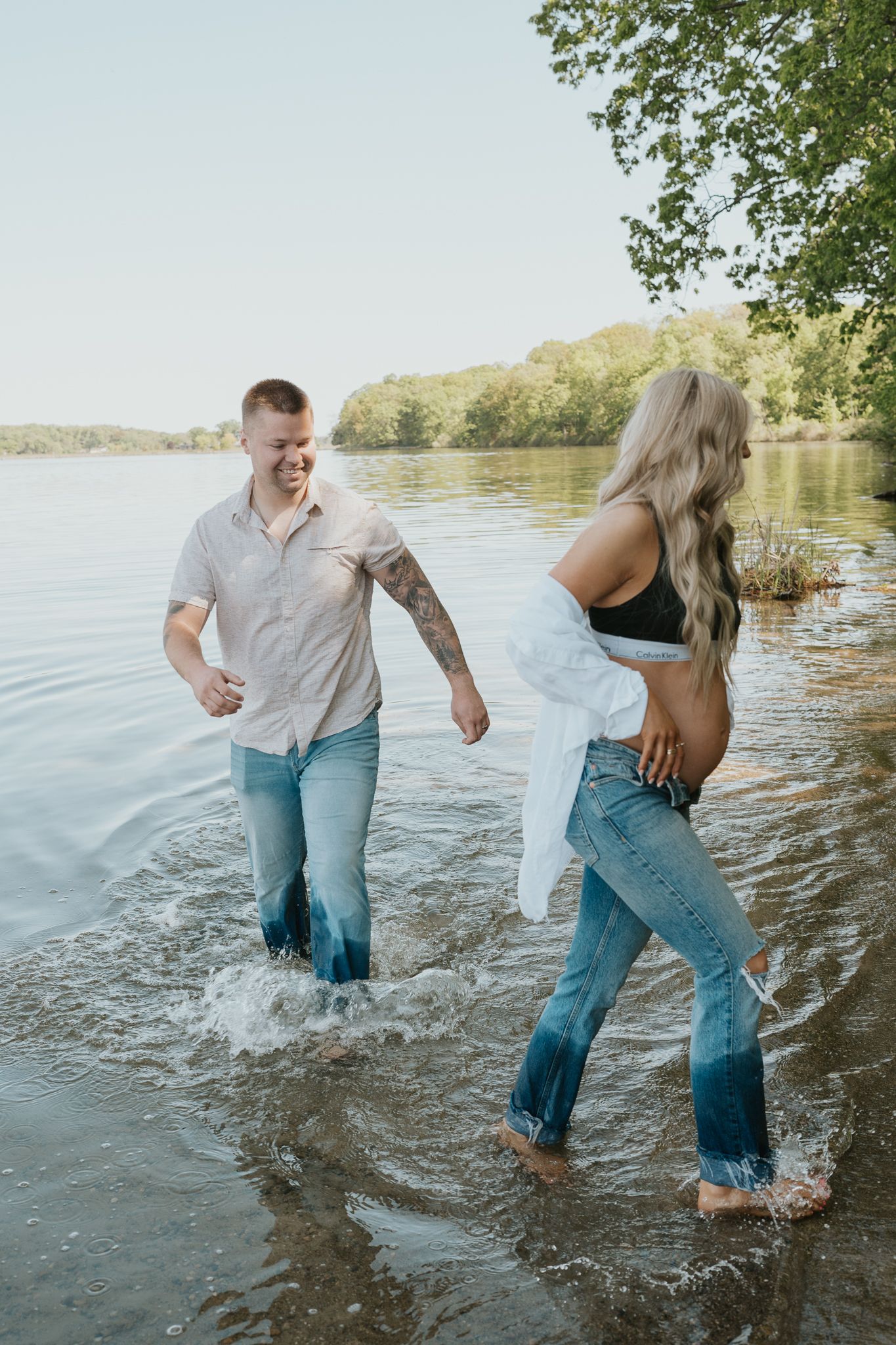 A playful couple splashing in shallow water at the edge of a lake in Angola IN.
