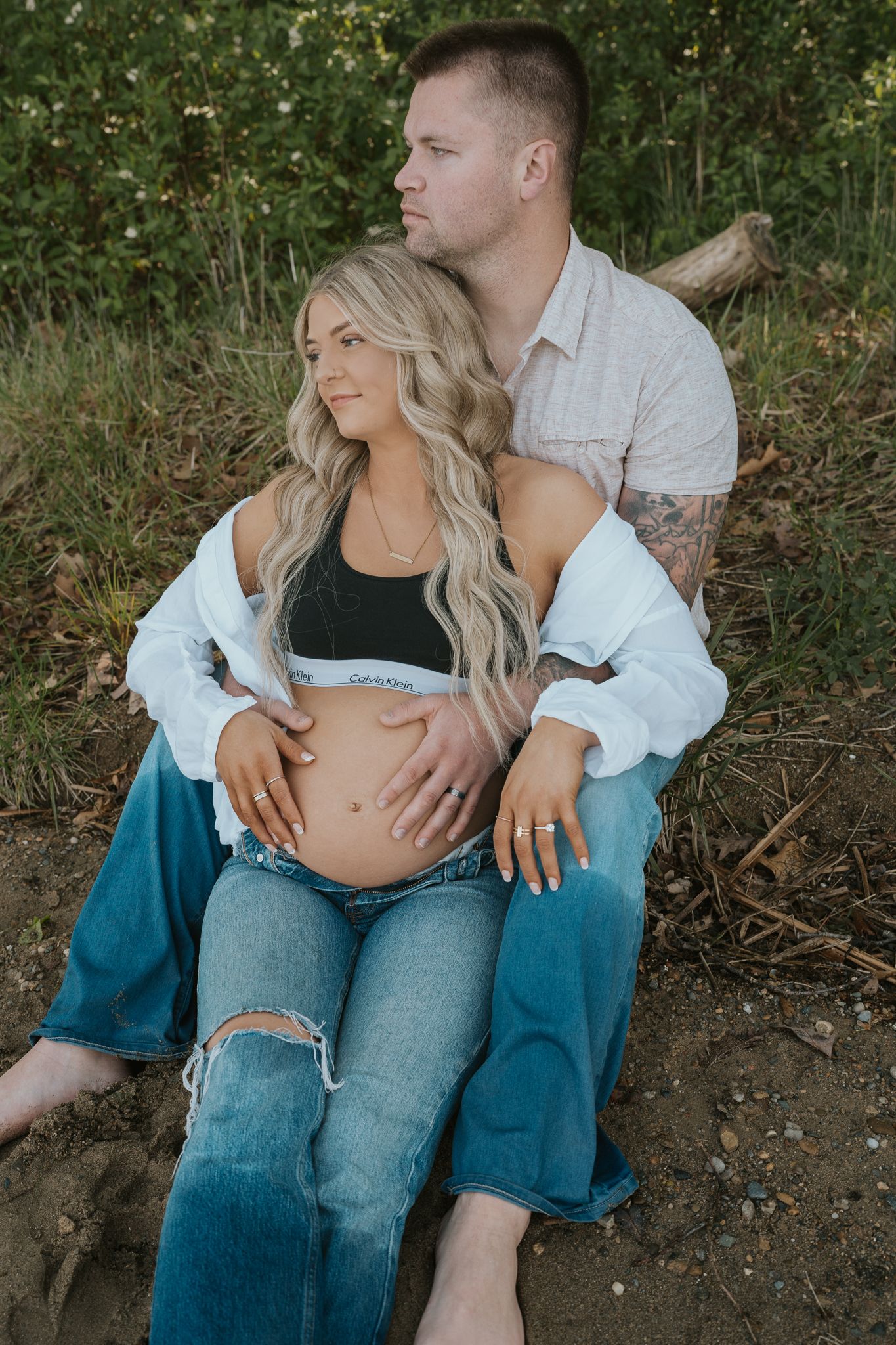 Romantic maternity photos in a lakefront setting with couple in casual attire.
