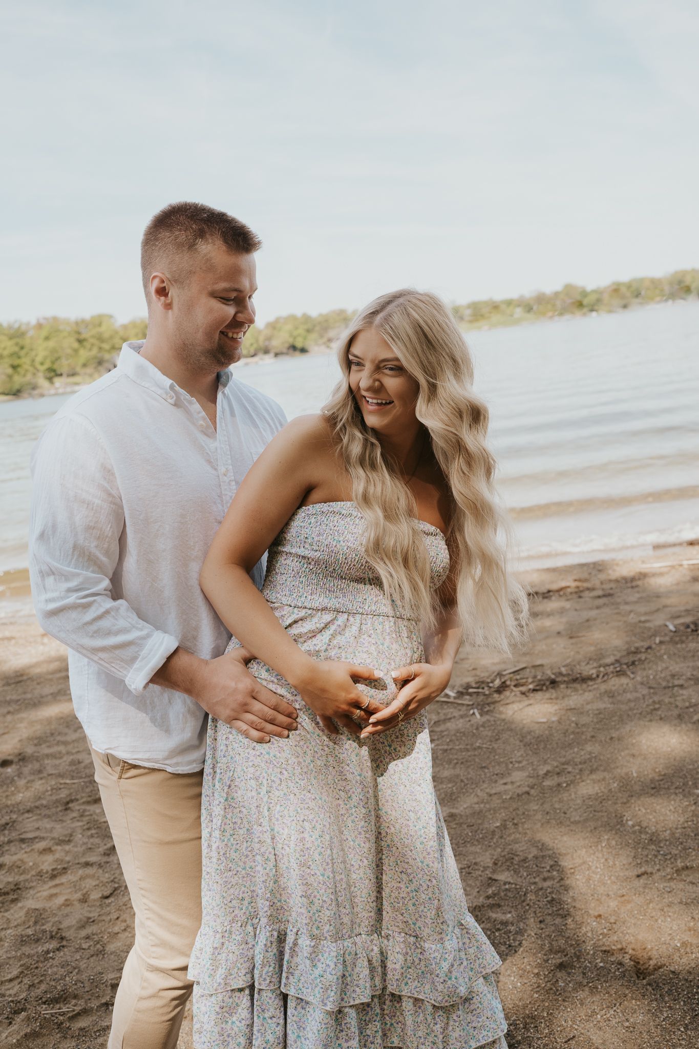 Maternity photoshoot on a beach with couple wearing white and beige outfits in northern Indiana.