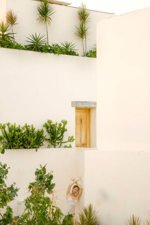 Minimalist white architecture with built-in planters showcasing tropical plants and succulents against cream-colored walls.
