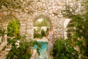 A lush tropical garden walkway with stone walls and hanging plants creates a serene outdoor pathway.