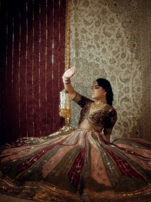Traditional wedding dress with intricate embroidery twirls in front of vintage wallpaper backdrop.