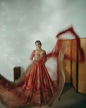 A traditional red and gold embroidered wedding dress is photographed in a dreamy, motion-blurred sequence against a mint wall.