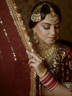 Close-up details of traditional Indian bridal jewelry and makeup with gold embellishments and red accents.