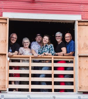 Two older couples surround a middle-aged couple on a barn balcony. They smile towards the photographer.