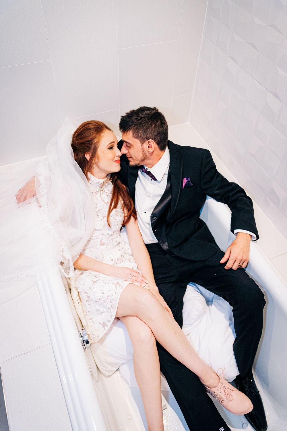Wedding Bride and groom stealing kisses and laughing in the hotel bathtub by Photogenic Fox Photography