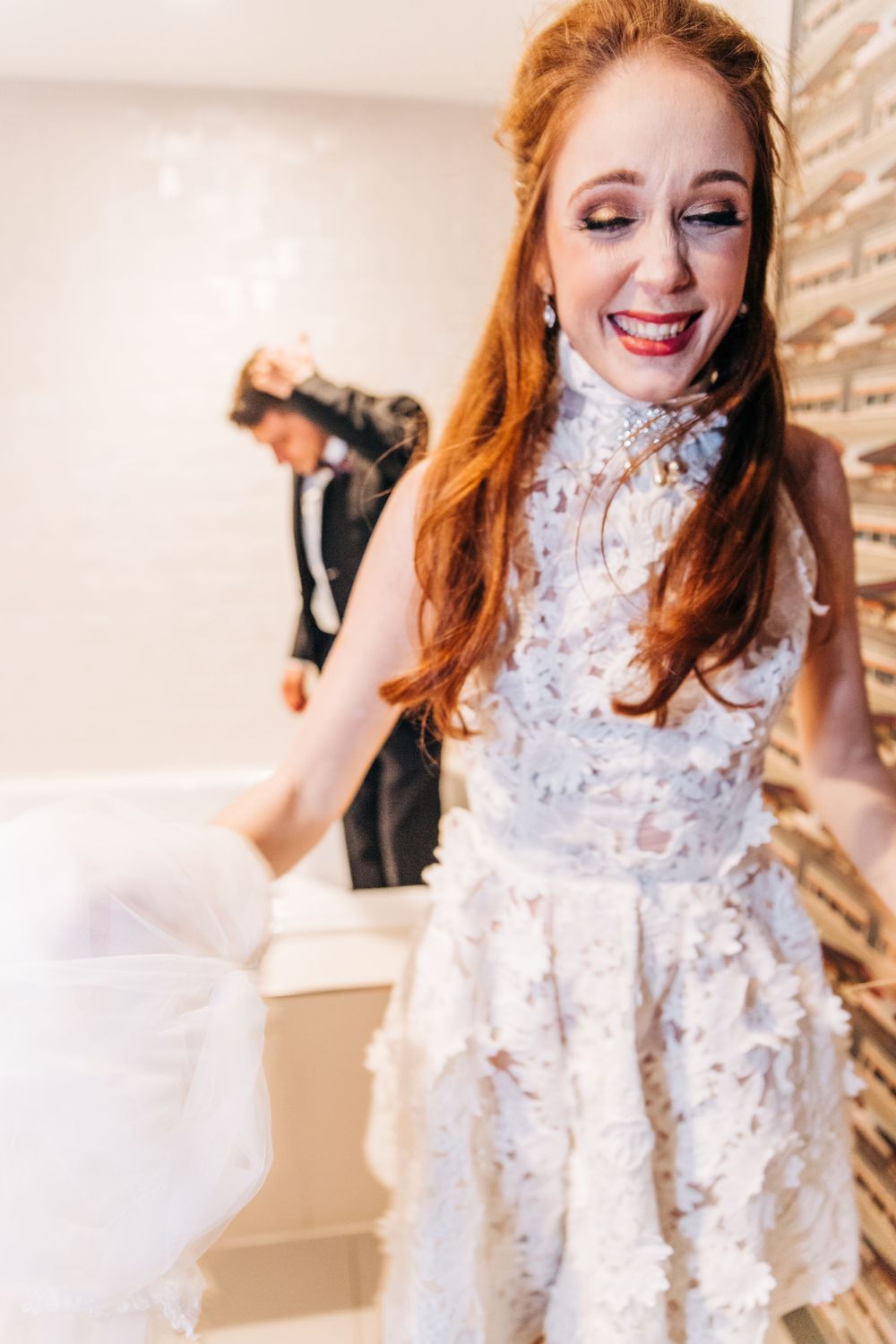 Wedding Bride laughing as she exits the hotel room bathtub and confused husband in background by Photogenic Fox Photography