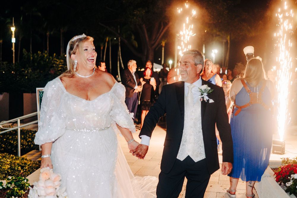 A wedding celebration with sparklers lighting up the night as a couple walks through at West Palm Beach Lake Pavilion