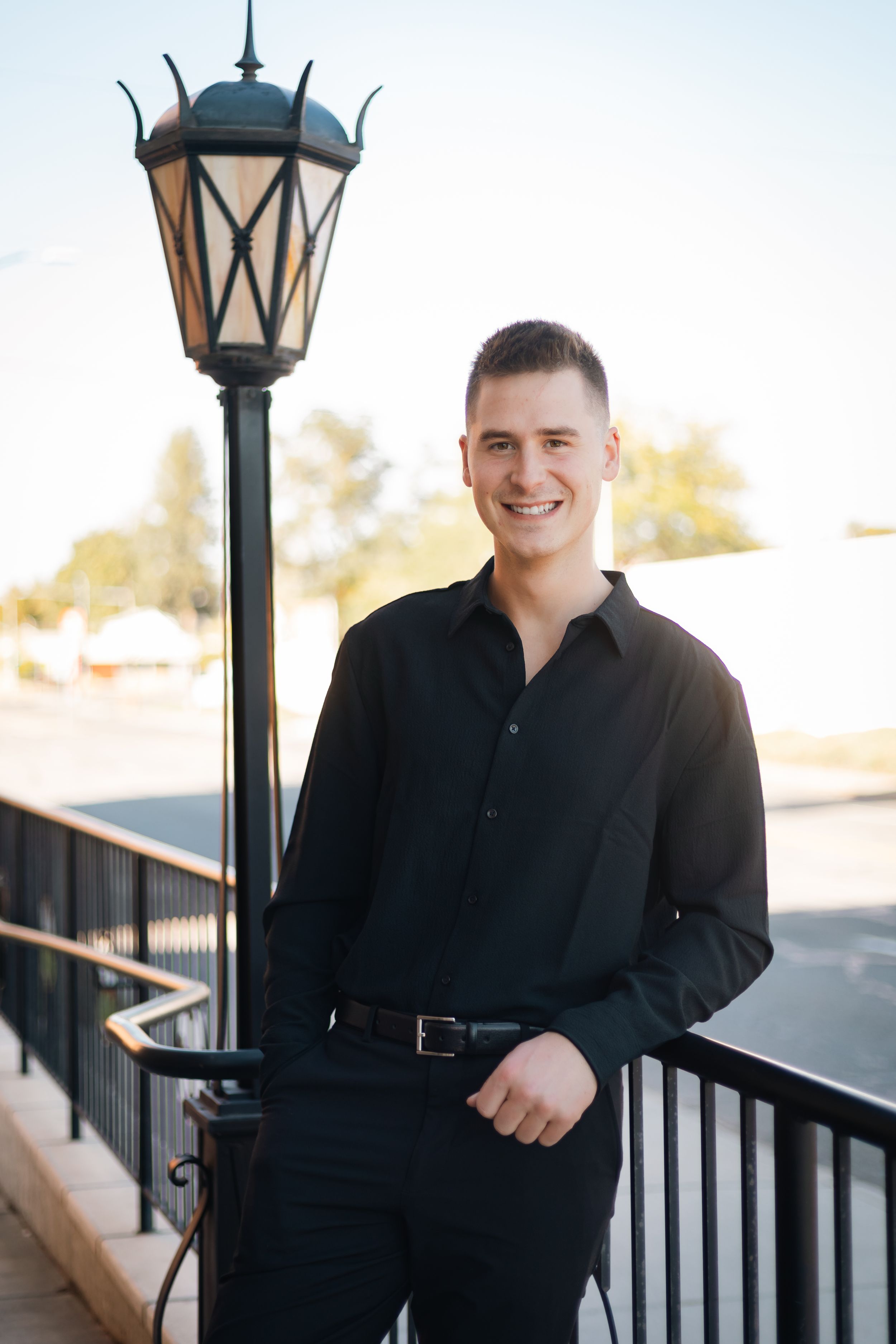 A casual portrait next to a decorative street lamp on a sunny afternoon.