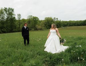 Bride and groom share a romantic moment in a lush green meadow on their wedding day.