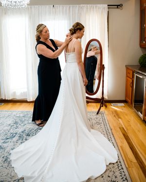 A wedding dress fitting scene with an elegant long-train gown reflected in a standing mirror.