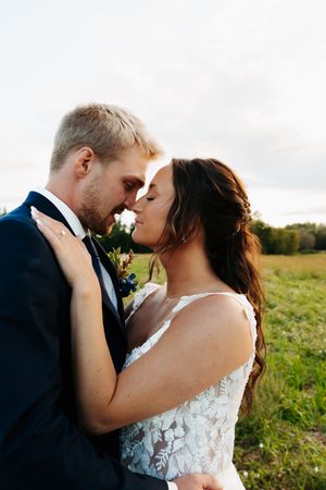 Intimate wedding portraits of a couple in a sunlit field with delicate lace dress details.