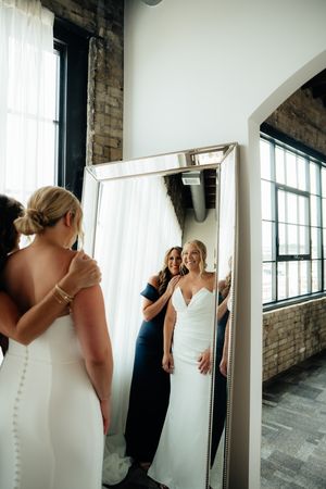A wedding preparation moment captured in a rustic venue with exposed brick and large mirrors.