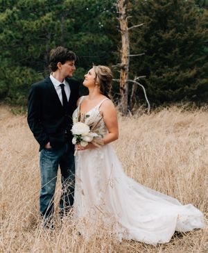 A couple shares an intimate moment in a field of golden grass during their wedding photoshoot.