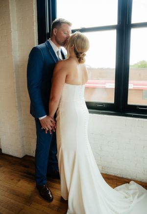 Elegant bride and groom share intimate moments in a bright industrial loft space with wooden floors.