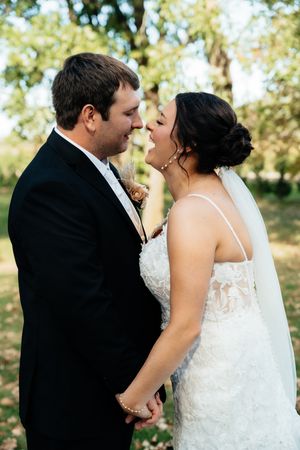 A joyful wedding couple shares an intimate moment together outdoors surrounded by greenery.