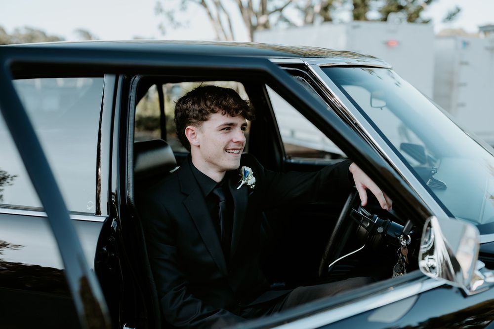 Black and white photo of someone sitting in the driver's seat of a car.