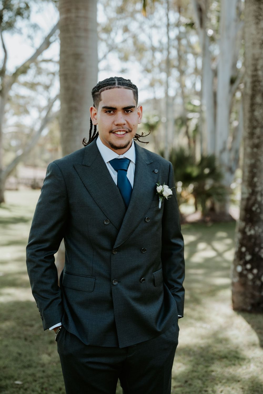 A formal event photo in a wooded setting with palm trees and natural lighting.