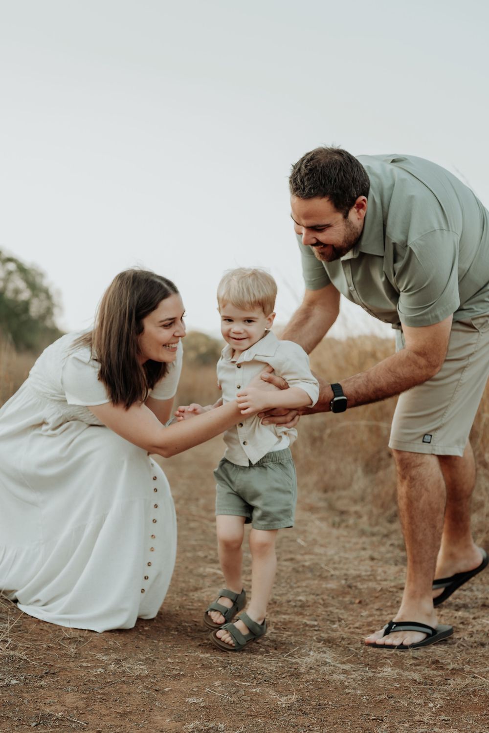 Family plays and laughs together during outdoor photo session in neutral colored clothing at calliope field.