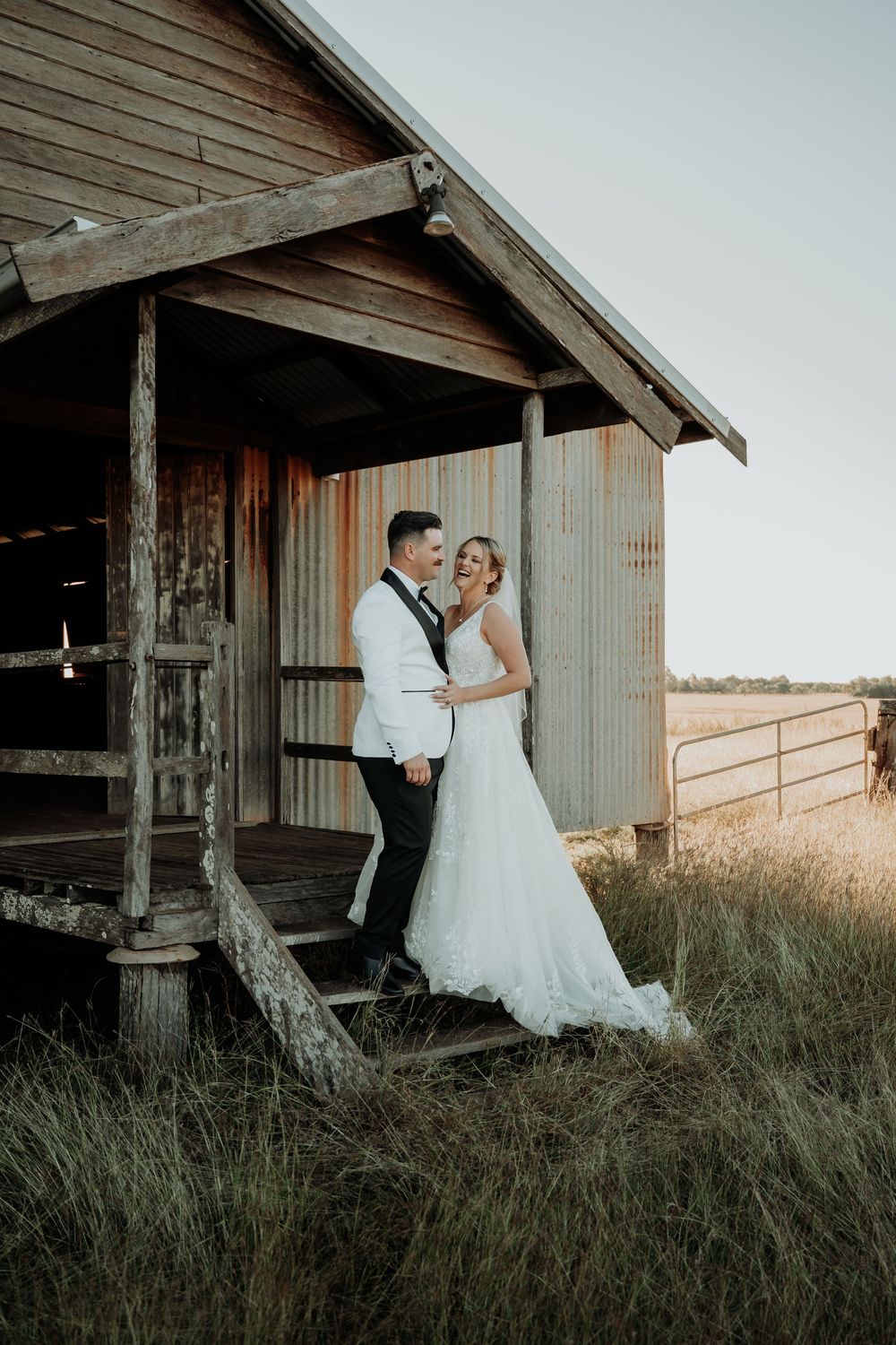 Newlyweds posing together on rustic wooden porch of weathered barn at hedlow retreat wedding venue.