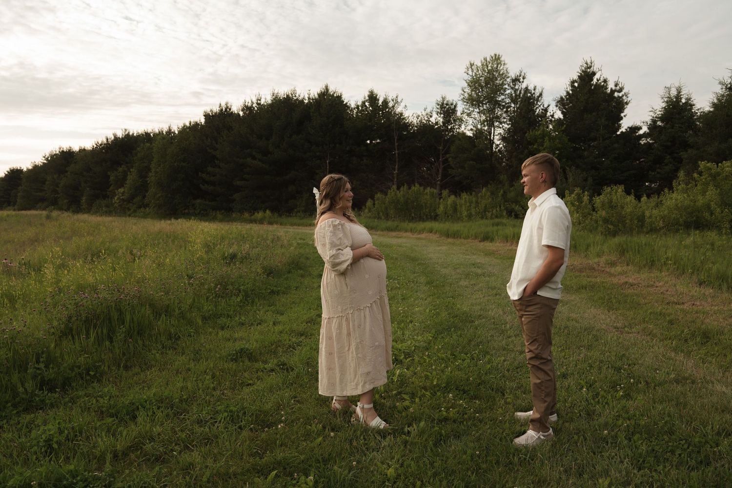 Couple embracing in outdoor field during golden hour photoshoot.