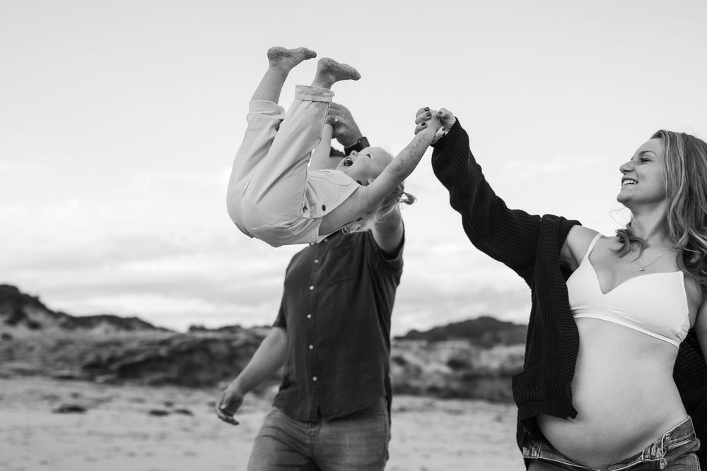 Black and white silhouettes of adults and children hold sparklers and dance together outdoors at dusk.