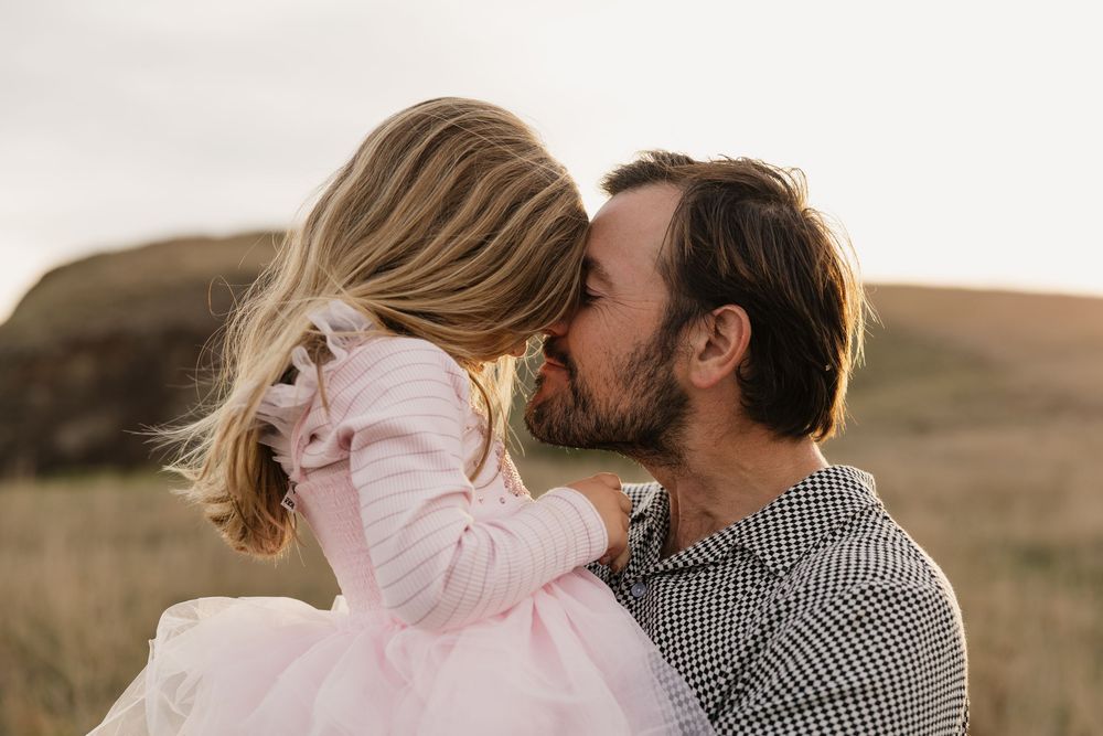 Family moments during golden hour photoshoot in outdoor cliff setting.