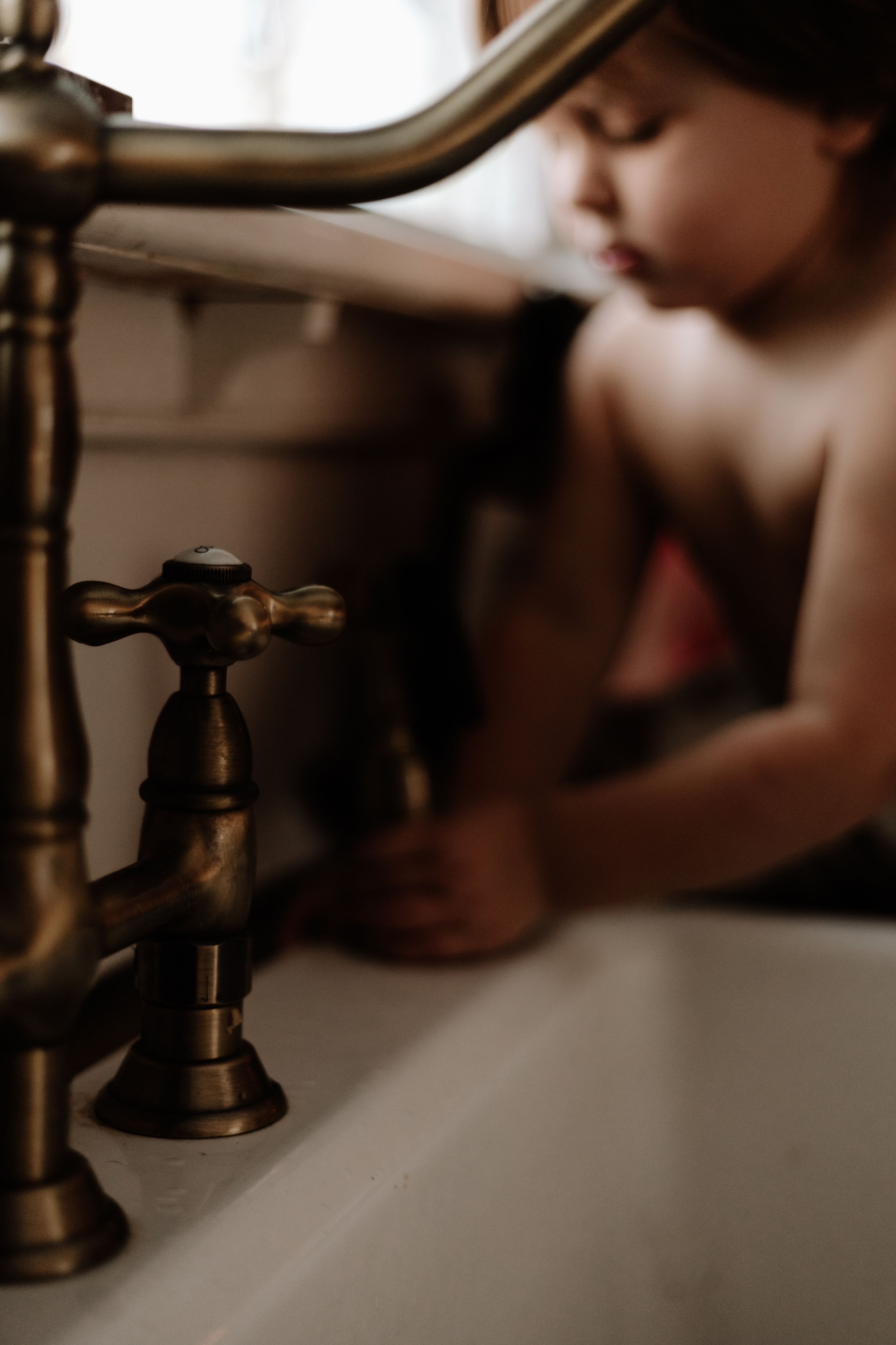 family photographer captures a little boy playing by the sink