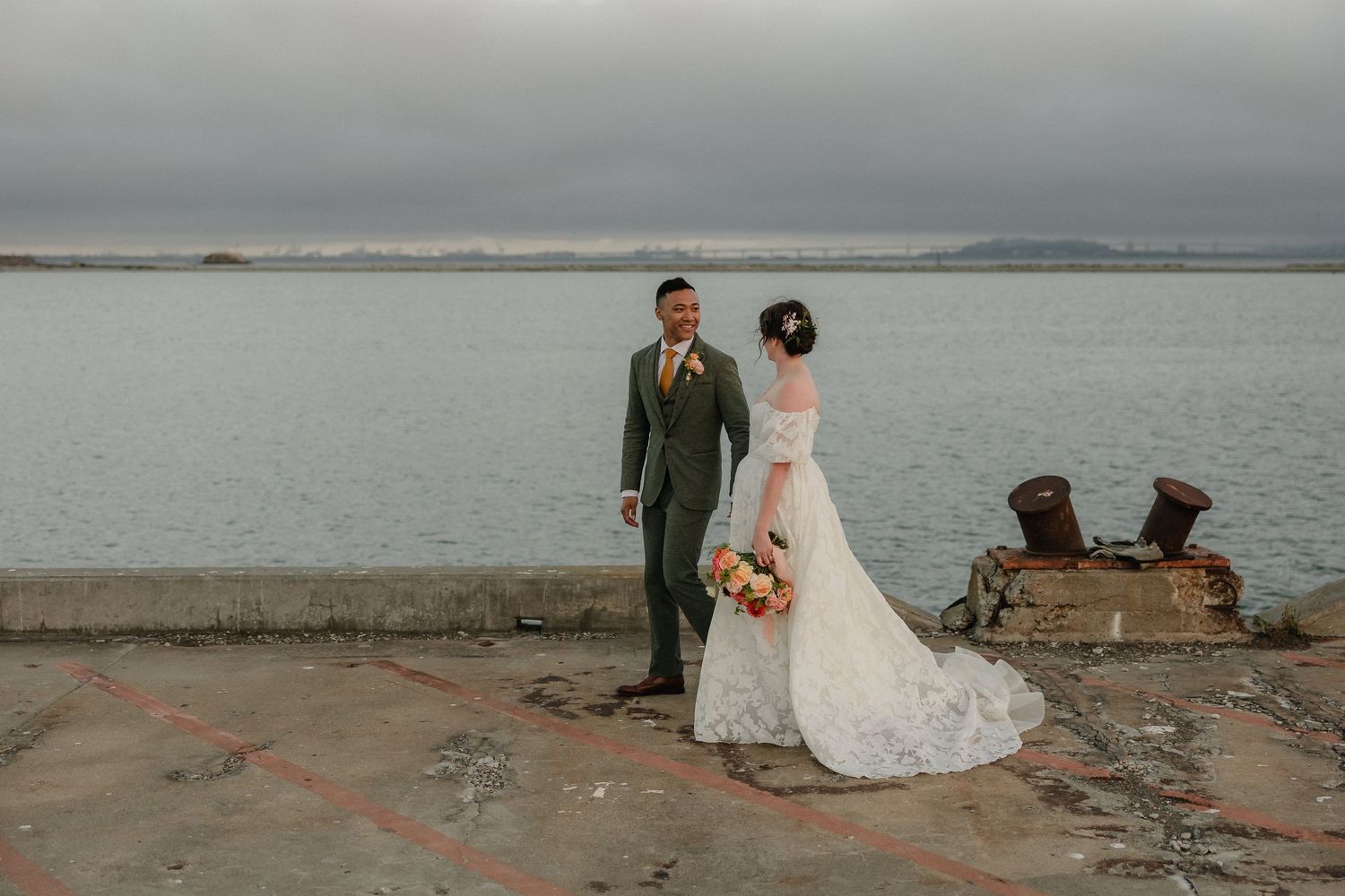 Bride holding colorful bouquet while sharing intimate moment with groom in golden sunlight.