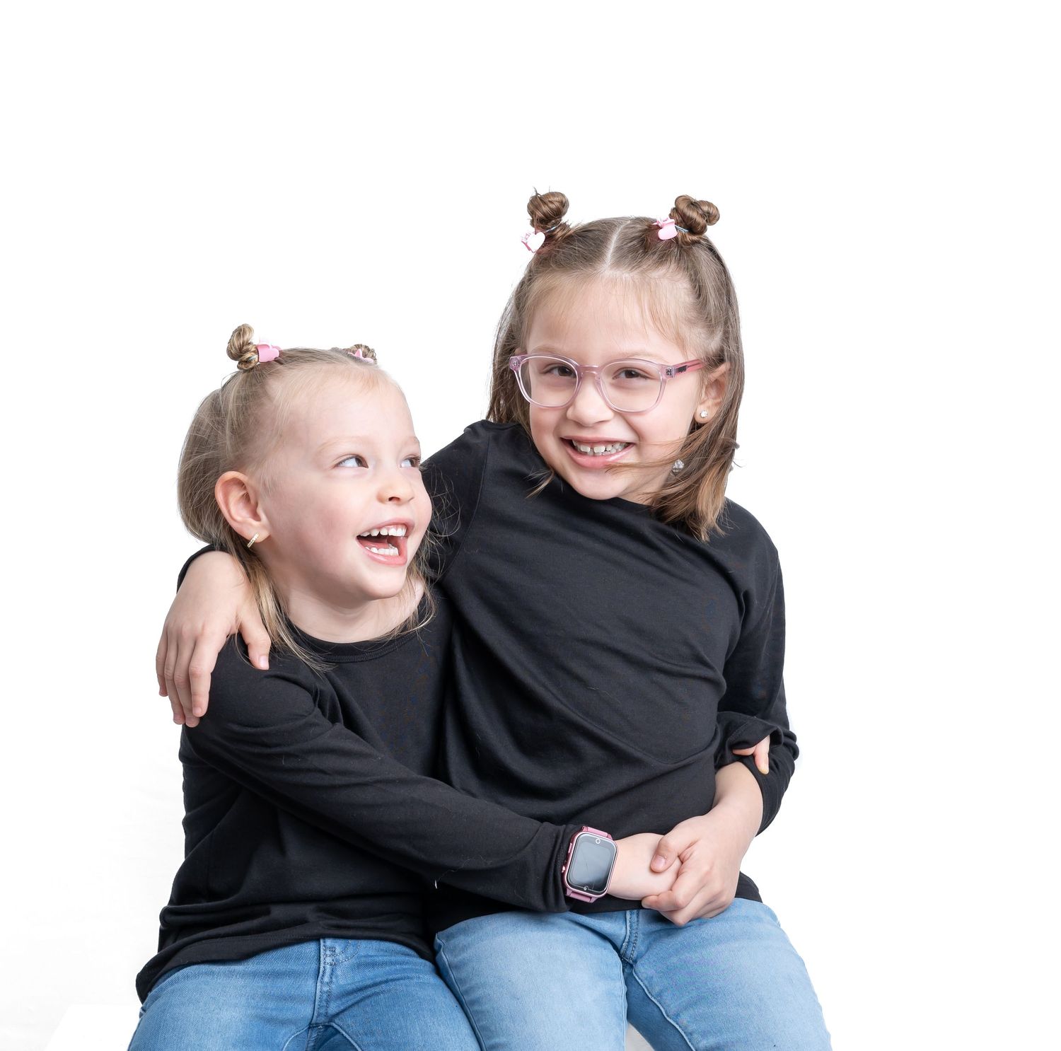 Two children in black sweaters share a joyful moment while sitting together.