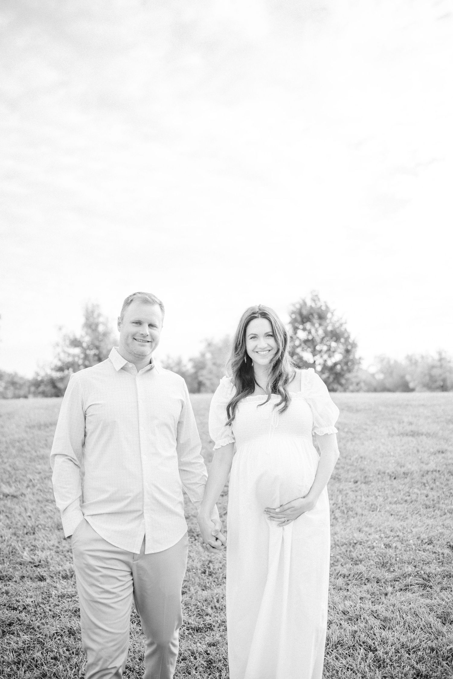 black and white image of pregnant mom brushing the hair out of her face.  standing under willow tree in carmel indiana