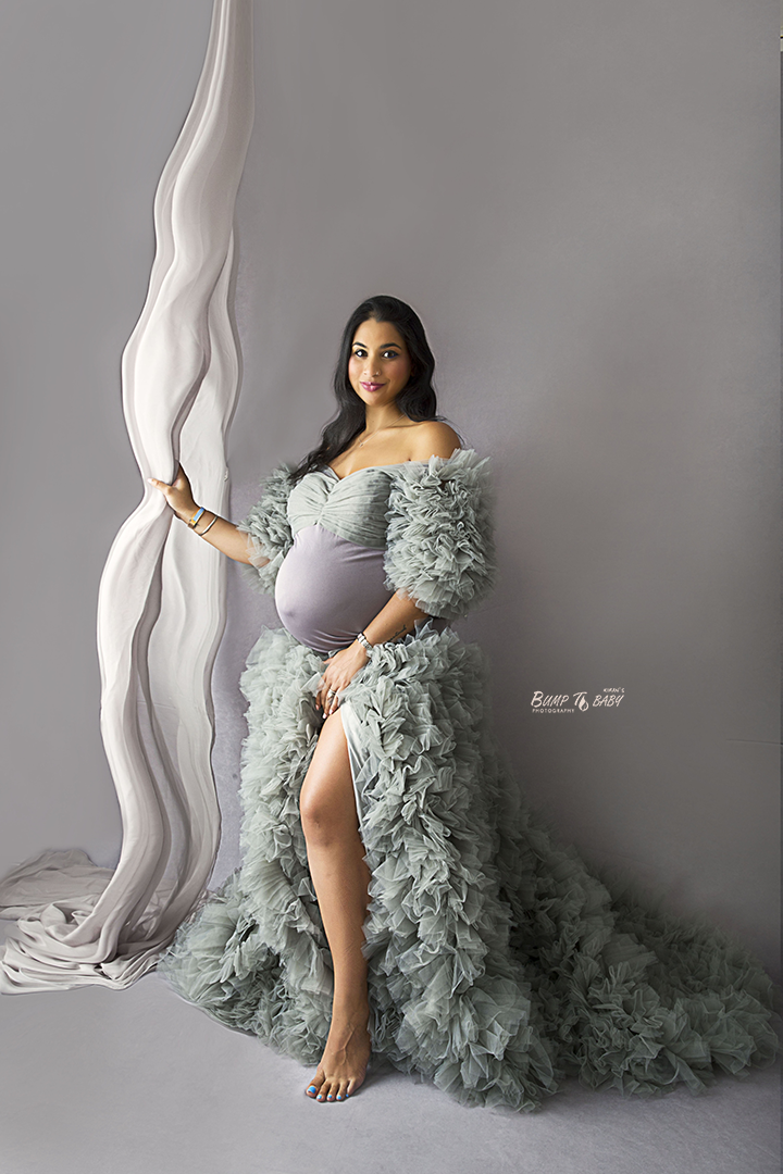 Family maternity portrait with toddler kissing mum’s baby bump in studio